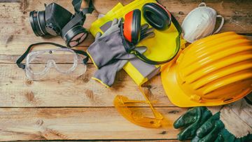 Hand hat, ear protection and other tools on a tabletop.